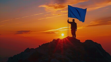 Silhouette of man holding blue flag on top of mountain, achievement and success concept.