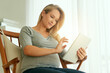 © TamJam/peopleimages.com - Typing, online and woman with tablet, pregnant and planning for birth of baby, smile and research. Digital, happy and person with app for learning of motherhood, health and growth of stomach in house