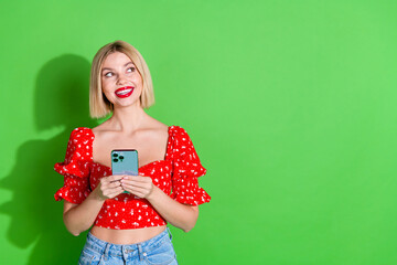 Wall Mural - Photo of gorgeous charming girl woman wear red trendy clothes hold gadget look empty space isolated on green color background