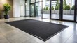 © Man888 - Clean and modern commercial establishment featuring a sleek black rubber floor mat with textured ridges and a subtle sheen, set against a light gray background.