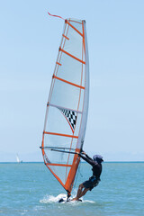 A windsurfer plays with the wind and ocean waves