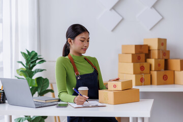 Wall Mural - Small business entrepreneur SME freelance asian woman working at home, check online, marketing, packaging, delivery, sell to customers, sme e-commerce concept.