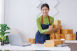 © David - Startup SME small business entrepreneur SME or freelance Asian woman standing using a laptop with box, online marketing packaging box and delivery, SME concept.