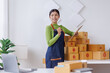 © David - Startup SME small business entrepreneur SME or freelance Asian woman standing using a laptop with box, online marketing packaging box and delivery, SME concept.