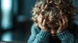 ©  Shomixer - A young child with curly hair covers their face with their hands, possibly expressing emotions such as shyness, sadness, or frustration in a soft-lit setting.