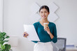 © David - Young successful employee business asian woman in blue shirt work hold takeaway delivery craft paper cup coffee to go stand at desk with laptop pc computer at office.