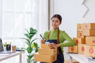 Wall Mural - SME business asian entrepreneurs small in Asia Write shipping information on a cardboard box in home office. Small business sme operators preparing to ship to customer