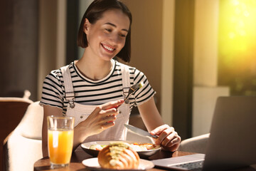 Canvas Print - Happy woman having tasty breakfast in cafe on sunny morning