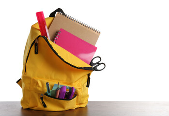 Sticker - Backpack with different school stationery on wooden table against white background, space for text