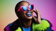© Pavel Lysenko - A joyous woman with striking blue lipstick and oversized pink sunglasses smiles brightly, wearing a vibrant outfit with colorful fur accents that enhance her lively expression