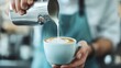©  Shomixer - A barista carefully pours milk into a cup of coffee, forming a heart shape, showcasing a moment of craftsmanship and detailed artistry in coffee culture.
