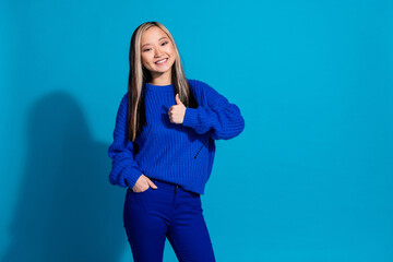 Wall Mural - Photo portrait of pretty young girl thumb up approve wear trendy knitwear outfit isolated on blue color background