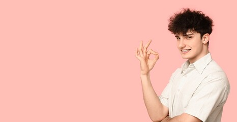 Poster - Young man with dental braces showing OK on pink background with space for text