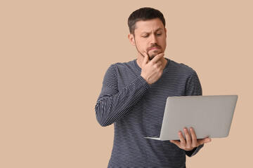 Poster - Thoughtful man with laptop on beige background