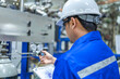 © reewungjunerr - Asian engineer working at Operating hall,Thailand people wear helmet  work,He worked with diligence and patience,she checked the valve regulator at the hydrogen tank.