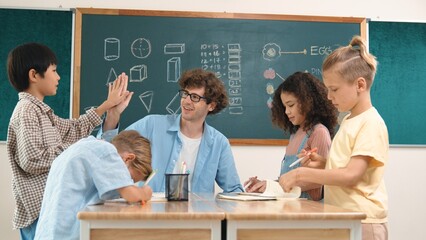 Wall Mural - Caucasian teacher giving high five to encourage children to working together. Group of diverse student high five with instructor and present classwork while drawing and writing mind mapping. Pedagogy.