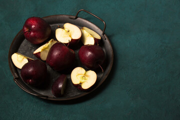 Red apples in a vintage tray on a green background