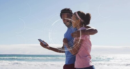 Couple on beach with smartphone, digital interface animation over them