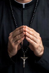 Sticker - Close-up of a priest's hands in prayer holding rosary beads soft light highlighting the beads and fingers symbolizing faith and devotion 