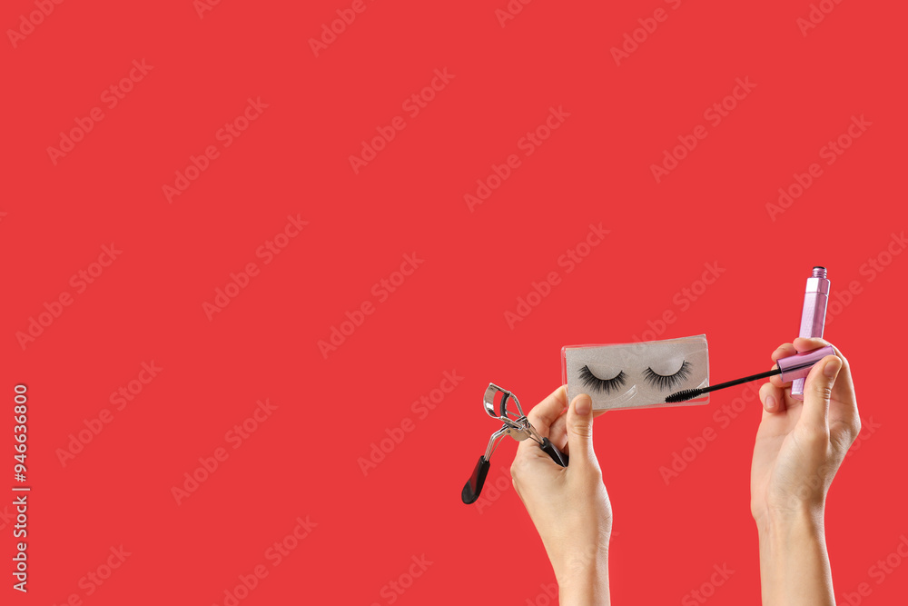 Woman with false eyelashes, curler and mascara on red background
