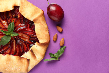 Wall Mural - Delicious plum galette with mint and almond on purple background