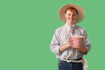 Young man dressed for Halloween with popcorn on green background