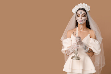 Wall Mural - Young woman dressed as dead bride for Halloween party holding candlestick with candle on beige background