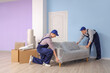 © Pixel-Shot - Loaders carrying grey sofa in room