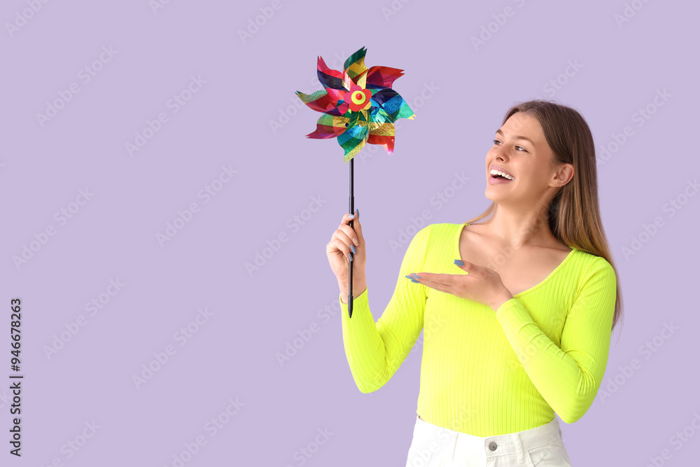 Young woman with toy windmill on lilac background