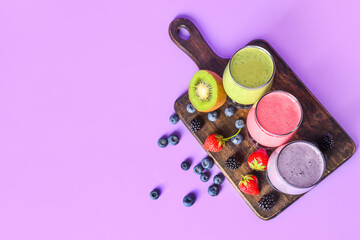 Wall Mural - Glasses of fresh smoothie with different berries on lilac background