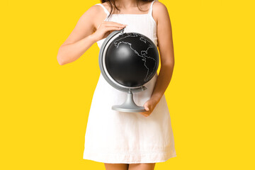 Wall Mural - Young Asian woman with globe on yellow background. Travel concept