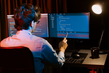 Working IT developer concentrating online software development information on surrounded by coding application pc screens, creating program for firmware on website at neon modern office home. Gusher.
