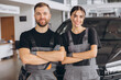 © anatoliycherkas - Auto car repair service center. Two happy mechanics - man and woman standing by the car