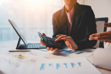 Wall Mural - Businesswoman analyzing financial data and using a calculator while working on a business project with her colleague