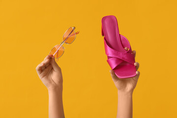 Poster - Female hands with stylish sunglasses and sandal on yellow background