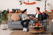 © Pixel-Shot - Father and his son dressed for Halloween exchanging gifts on sofa at home