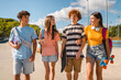 © InsideCreativeHouse - Group of positive teenagers high school pupils friends classmates college students boys and girls with bags skateboards walking in urban street hanging out together talking speaking with each others