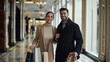 © awais - Young couple shopping, holding bags, woman in beige turtleneck, man in black coat, smiling, elegant look, indoor corridor.