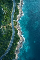 Wall Mural - Aerial view of a coastal road winding along a rocky shoreline and turquoise waters.