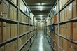 © nsit0108 - Rows of shelves holding cardboard boxes containing files fill a storage room with a narrow aisle for access