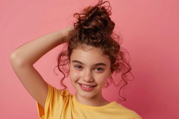 Wall Mural - A young girl with curly hair and a bright yellow shirt, smiling or looking directly at the camera