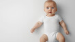 © Sean - Baby wearing white onesie lying on back on white background