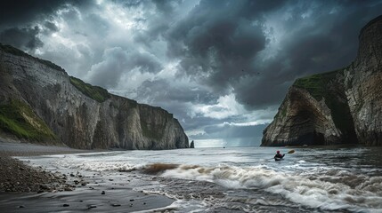 Kayaker paddling in the ocean with dramatic cliffs and storm clouds