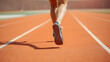 © Tark - Close up of back view of woman's feet in sport shoes running on orange running track. Generative AI