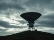 © cochisevisuals - A large satellite dish on a hilltop against a stormy sky.
