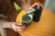 © Leo Lintang - A woman is holding a mug and a device for pouring water from the water gallon