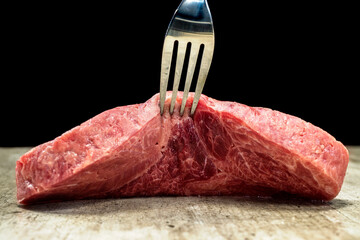 A fork is sticking out of a piece of sirloin meat