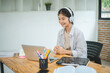 © photobyphotoboy - Teenage Asian students  wearing a headphone are communicating through video conferencing for online learning. In a video conference call via apps.