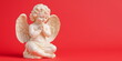 © Vasiliy - Praying cherub figurine with wings on vibrant red background. Valentine's Day decorations, religious gift ideas and romantic home decor concepts. Place for text