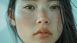 © MyDorkyDolphin - A close-up portrait of an Asian model with flawless skin, wearing minimal makeup and a soft expression, set against a neutral, blurred background. 8k UHD, suitable for high-quality printing